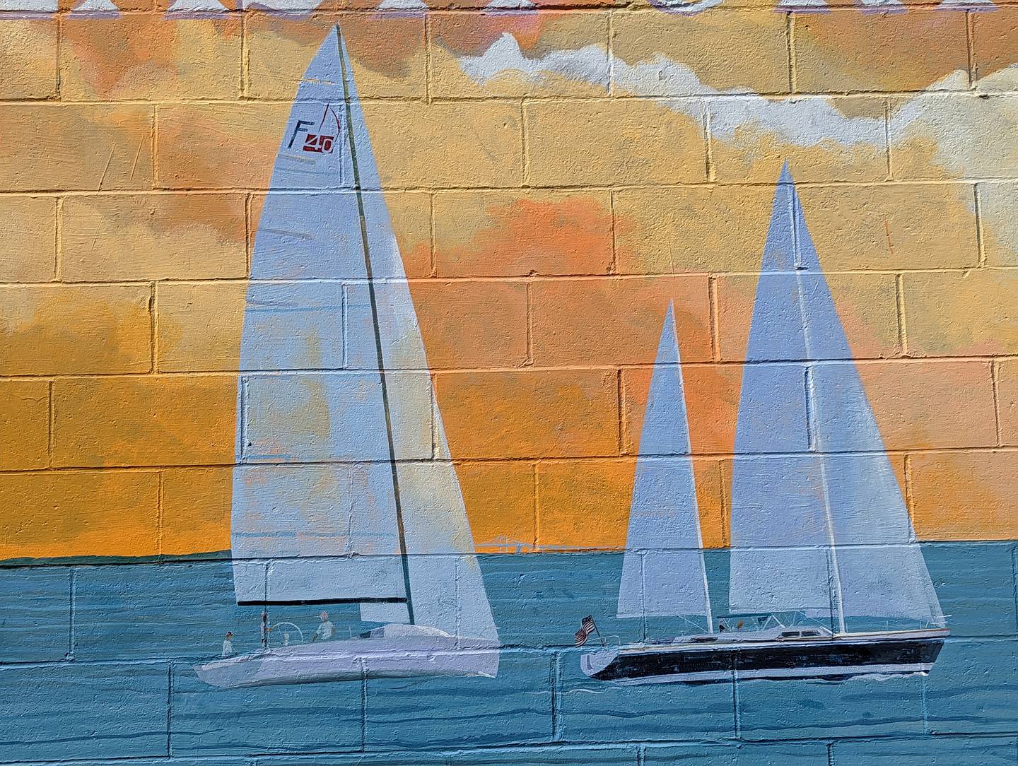 A section of Cindy Holden Fletcher's Eastport anniversary mural depicts sailboats against an orange sunset.