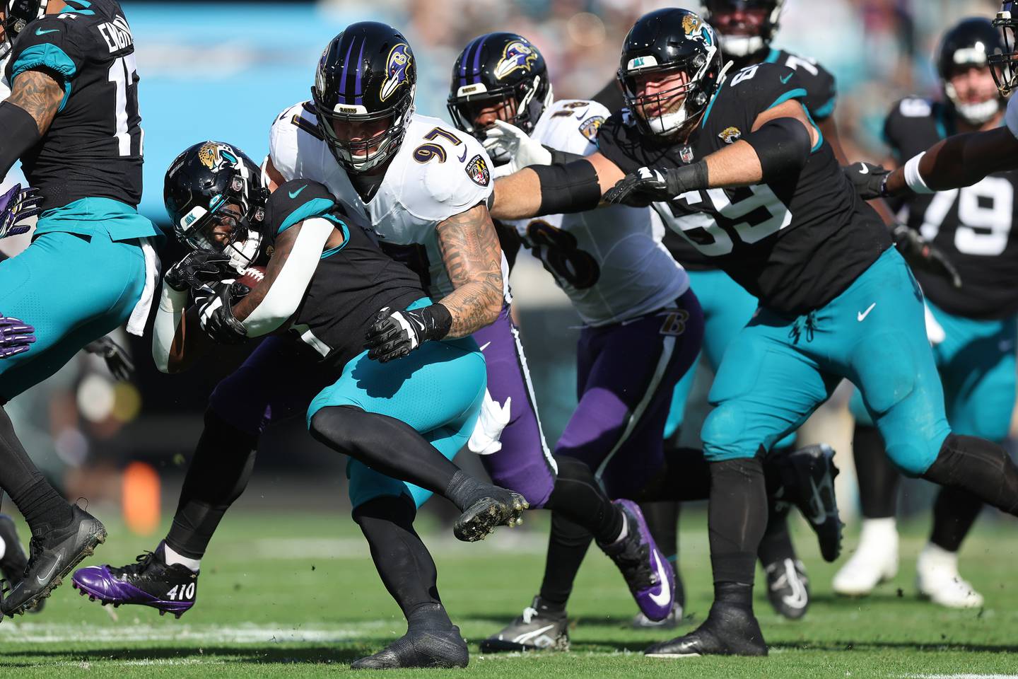 JACKSONVILLE, FLORIDA - NOVEMBER 27: Travis Etienne Jr. #1 of the Jacksonville Jaguars is tackled by Brent Urban #97 of the Baltimore Ravens during the first half at TIAA Bank Field on November 27, 2022 in Jacksonville, Florida.