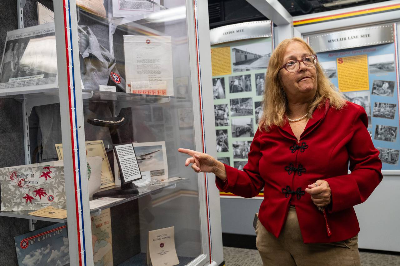 Debi Wynn gives a tour of the Glenn L. Martin Aviation Museum and points into a case that contains artifacts from Rosies.