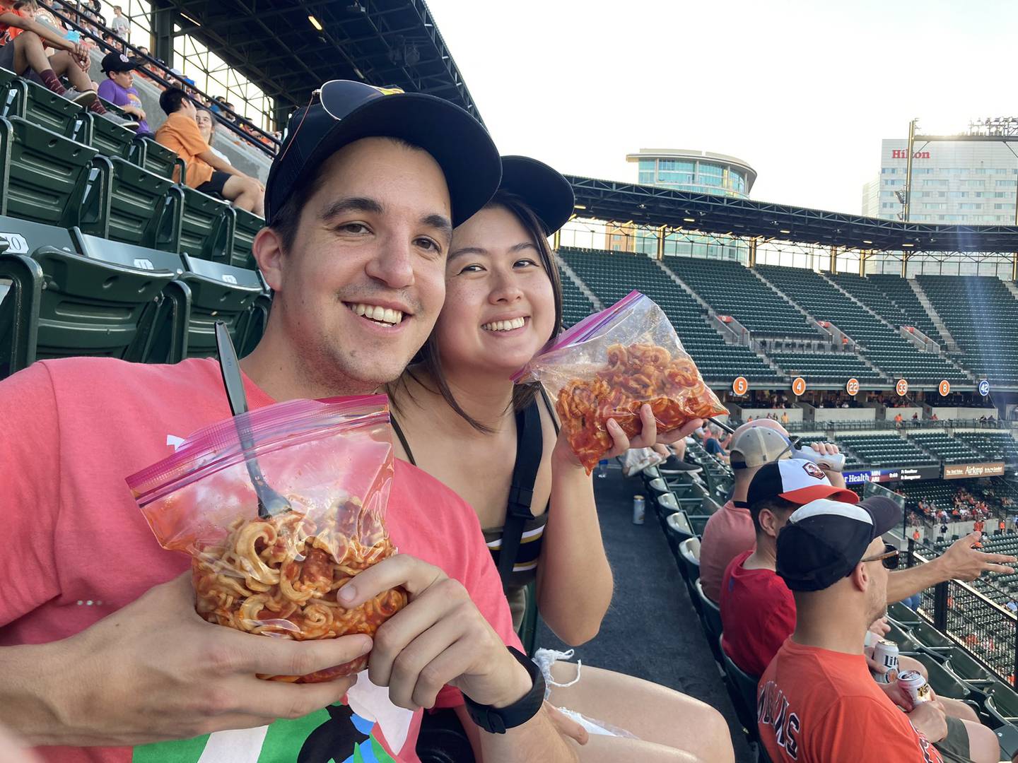 Baltimore Banner reporter Alissa Zhu and Baltimore Sun reporter Giacomo Bologna show off their Ziploc bags of spaghetti at an Orioles game.