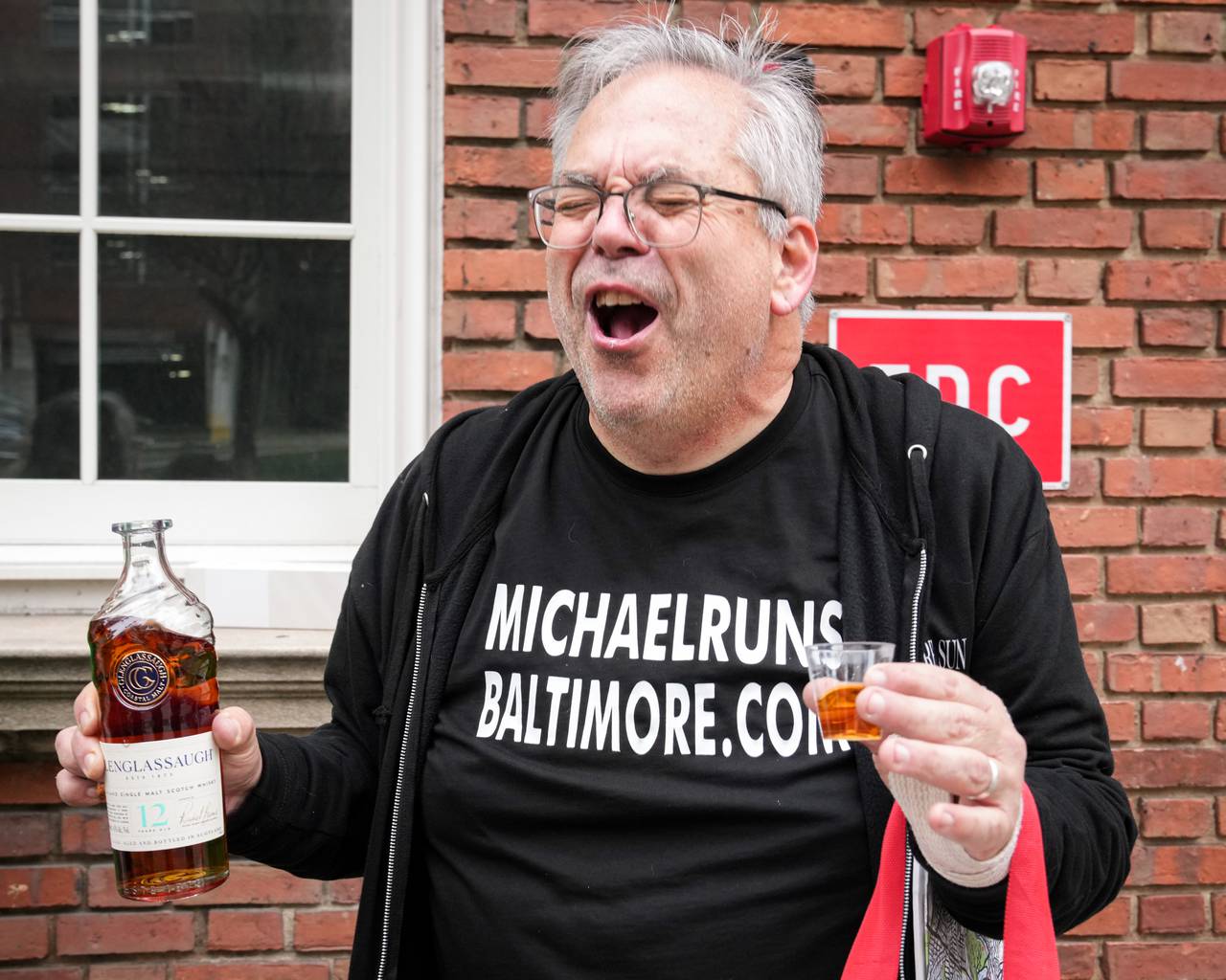 Michael Lisicky reacts after taking a shot of celebratory whiskey at the top of Dark Lane in downtown Baltimore on February 12, 2024. For the last eight months, Lisicky has been working to complete his goal of running on every street in Baltimore.