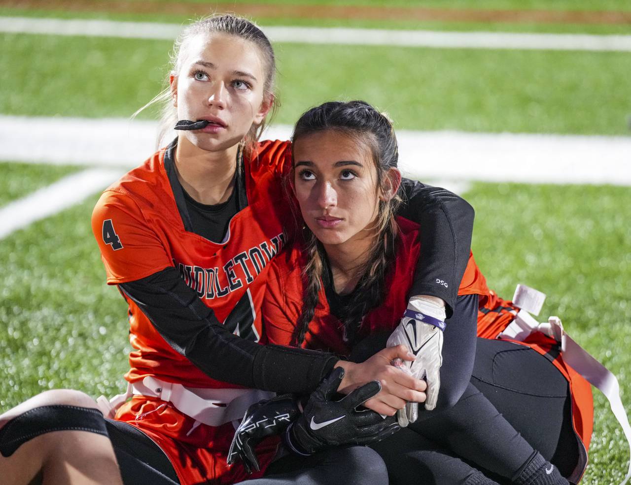 Middletown’s Genevieve Chase (4) and Chloe Lee (9) keep each other warm at half time during the Girls flag semifinals at the Under Armour’s “The Stadium at the House” in Baltimore, Wednesday.
