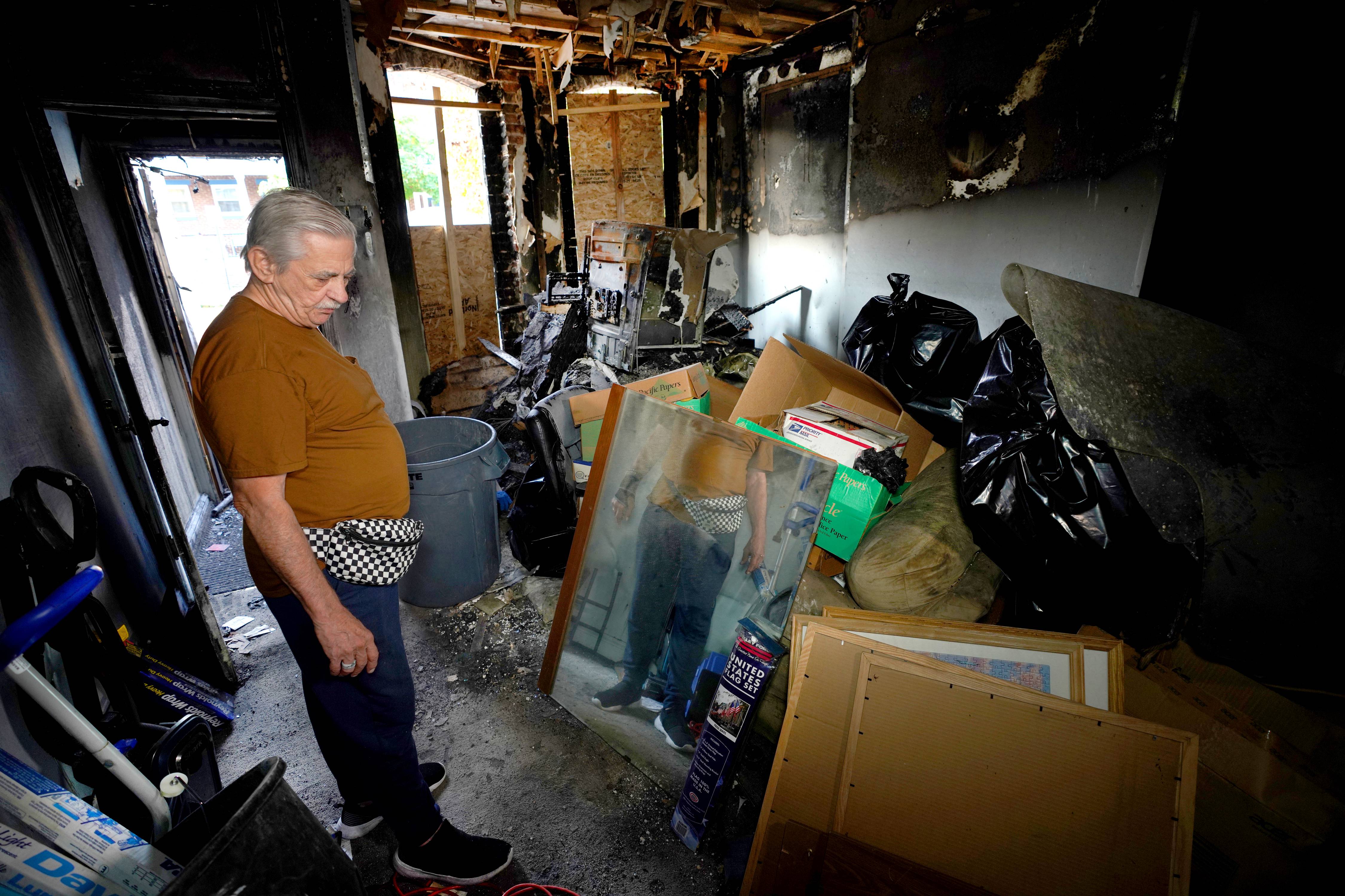 John Washko, one of the victims of the fire, is photographed in the burned out home and looks for salvageable items from the fire.