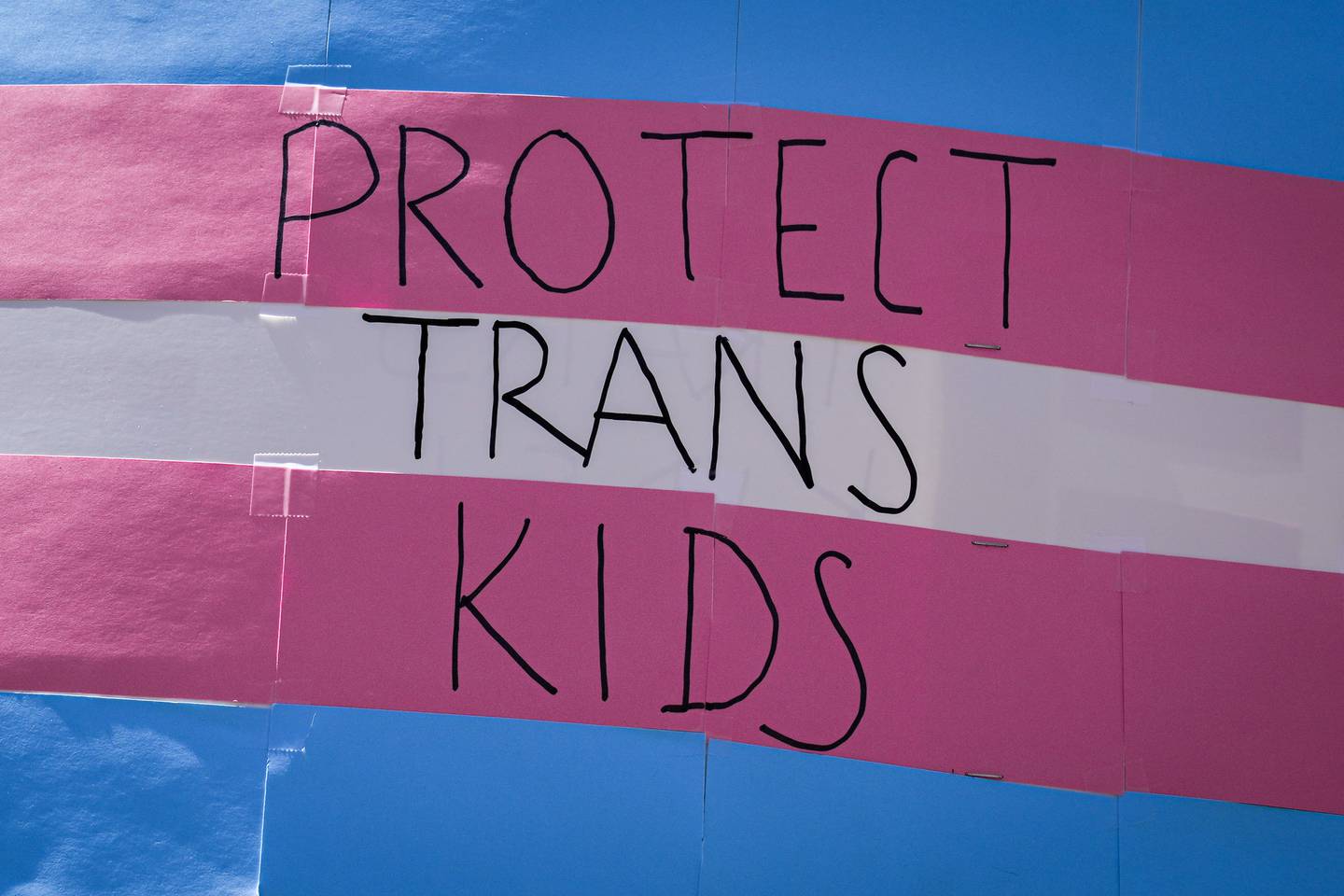 A parent holds up a sign reading “protect trans kids” on June 4 at Baltimore Trans Pride 2022.