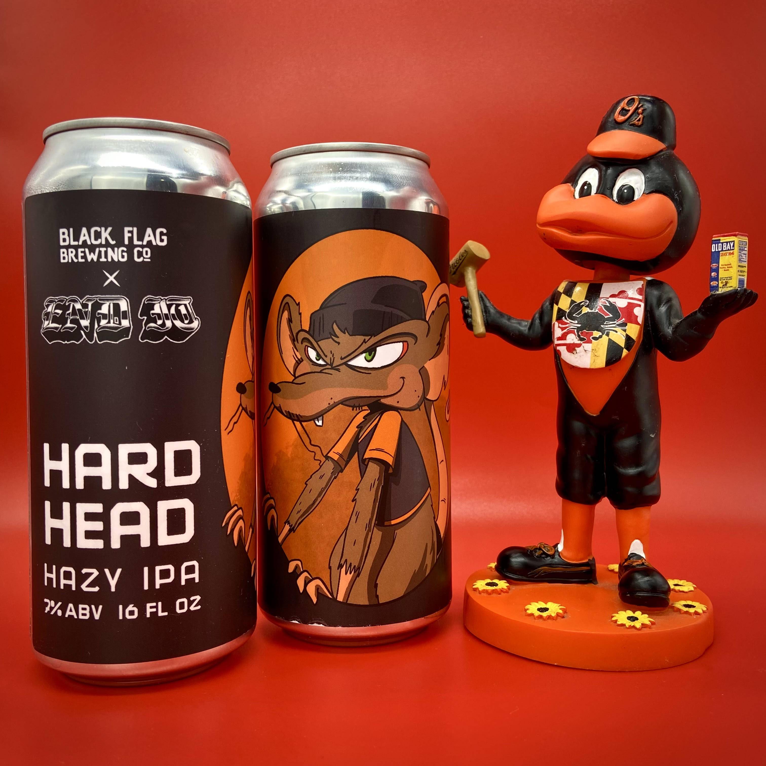 Two cans of the Hard Head hazy IPA from Black Flag Brewing Co. are pictured next to a a bobblehead of the Oriole Bird holding a mallet and can of Old Bay.