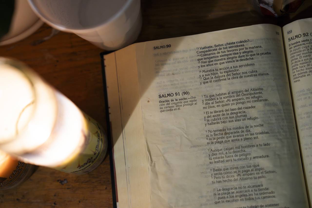 A Bible open to Psalm 90 - The Night Prayer sits on an altar that houses photos of  Angel Gustavo Adolfo Paz Gutierrez, 8, and Yeymi Rubi Gutierrez Paz, 13 and their cousin Jeremías Gutierrez Gomez, 22. They all died in a house fire in the early morning hours of February 27.