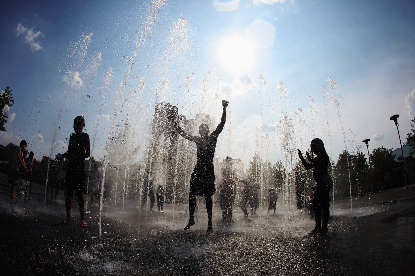 A group of people cool off in a fountain at the Inner Harbor.