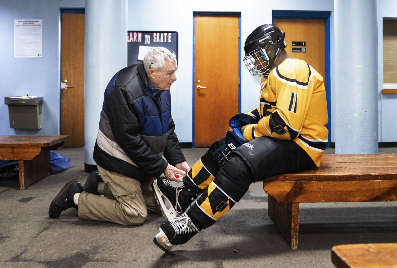 Founder of the Baltimore Banners, Noel Acton, helps adjust the skates of Donteze Branch, before a game at Mimi DiPietro Family Skating Center, in Baltimore, February 5, 2023.
