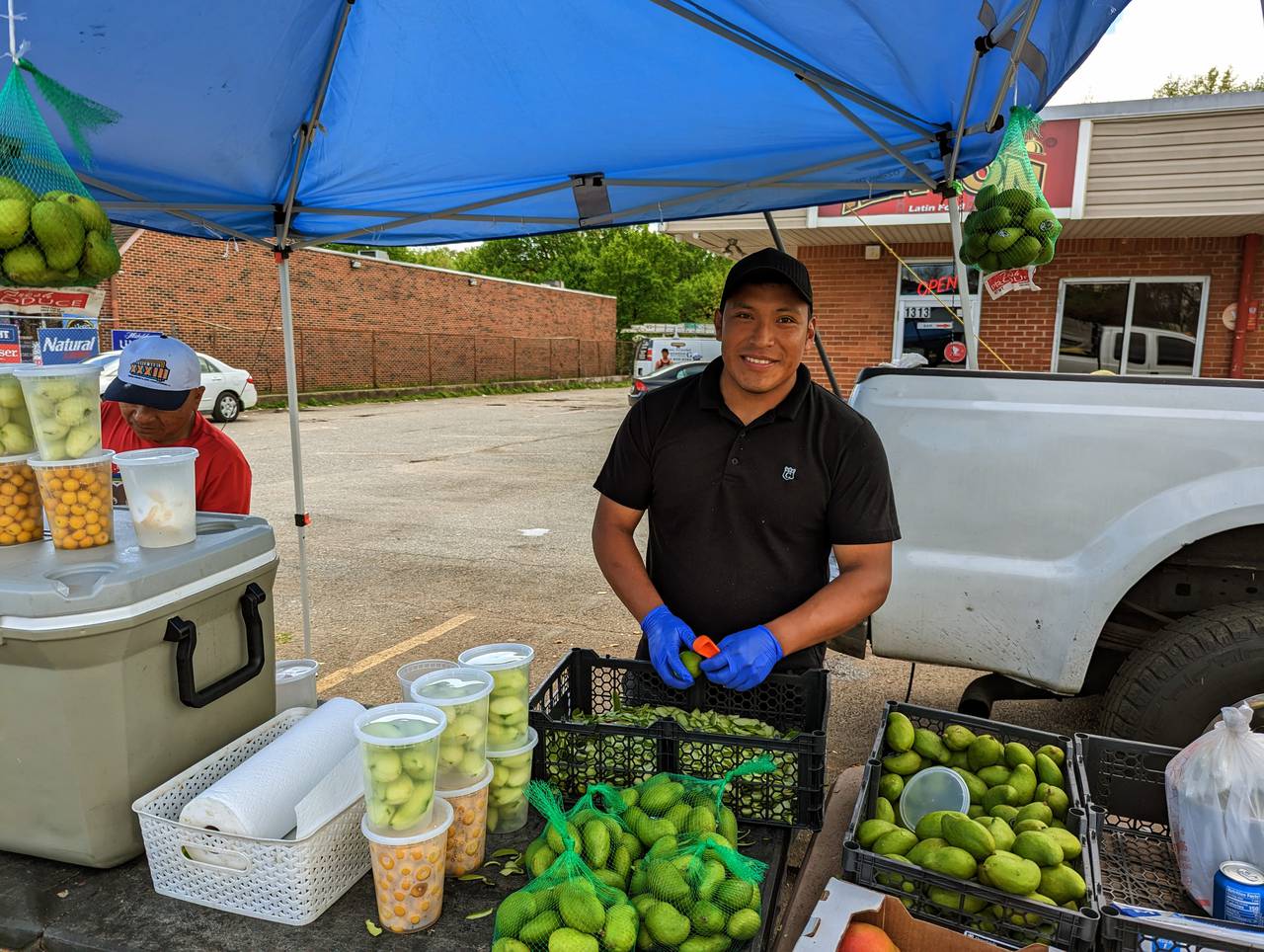 Mateus cuts up green mangos for sale outside a small tienda and laundry on Forest Drive, where some neighborhoods are home to the city's Hispanic population.