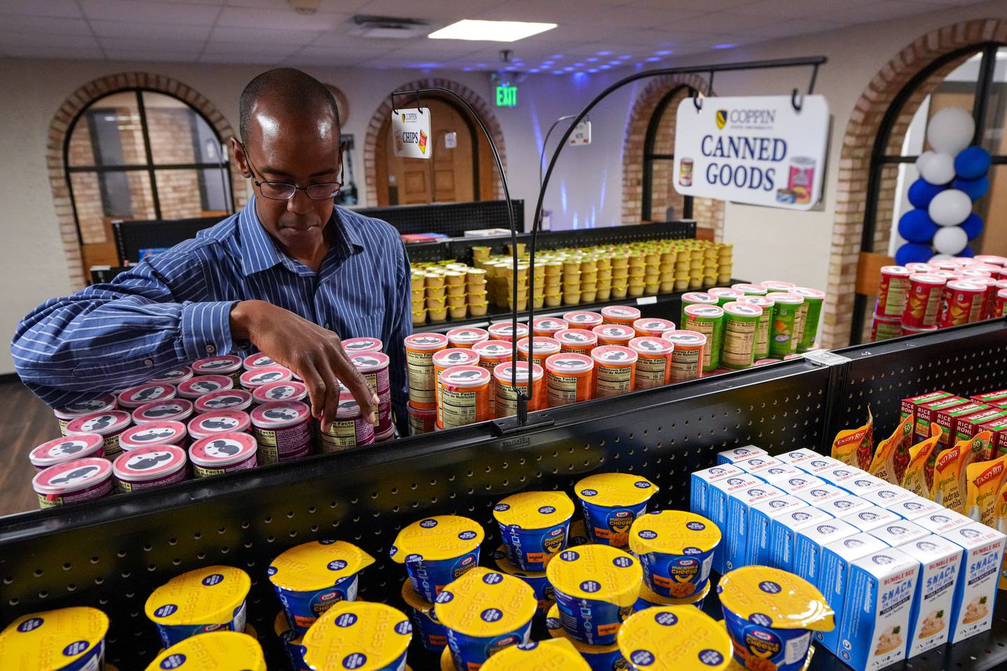 Christopher Thomas, Assistant Director, Center for Counseling and Student Development, restocks Pringles chips inside Coppin State’s brand new “Coppin Corner” resource center on May 31, 2023. To help students facing food insecurities, Coppin State University just recently launched the Coppin Corner, a food resource center that carries non-perishable food items, frozen foods, personal hygiene products and cleaning supplies