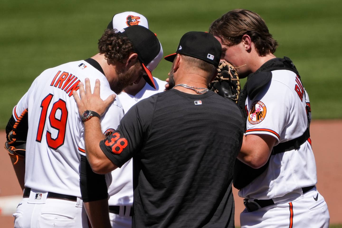 Baltimore Orioles starting pitcher Cole Irvin (19) checks in with teammates and pitching coach Chris Holt (38) during a timeout in a baseball game against the Oakland Athletics at Camden Yards on Wednesday, April 12. This was the fourth game in a series the Orioles played against the Athletics.