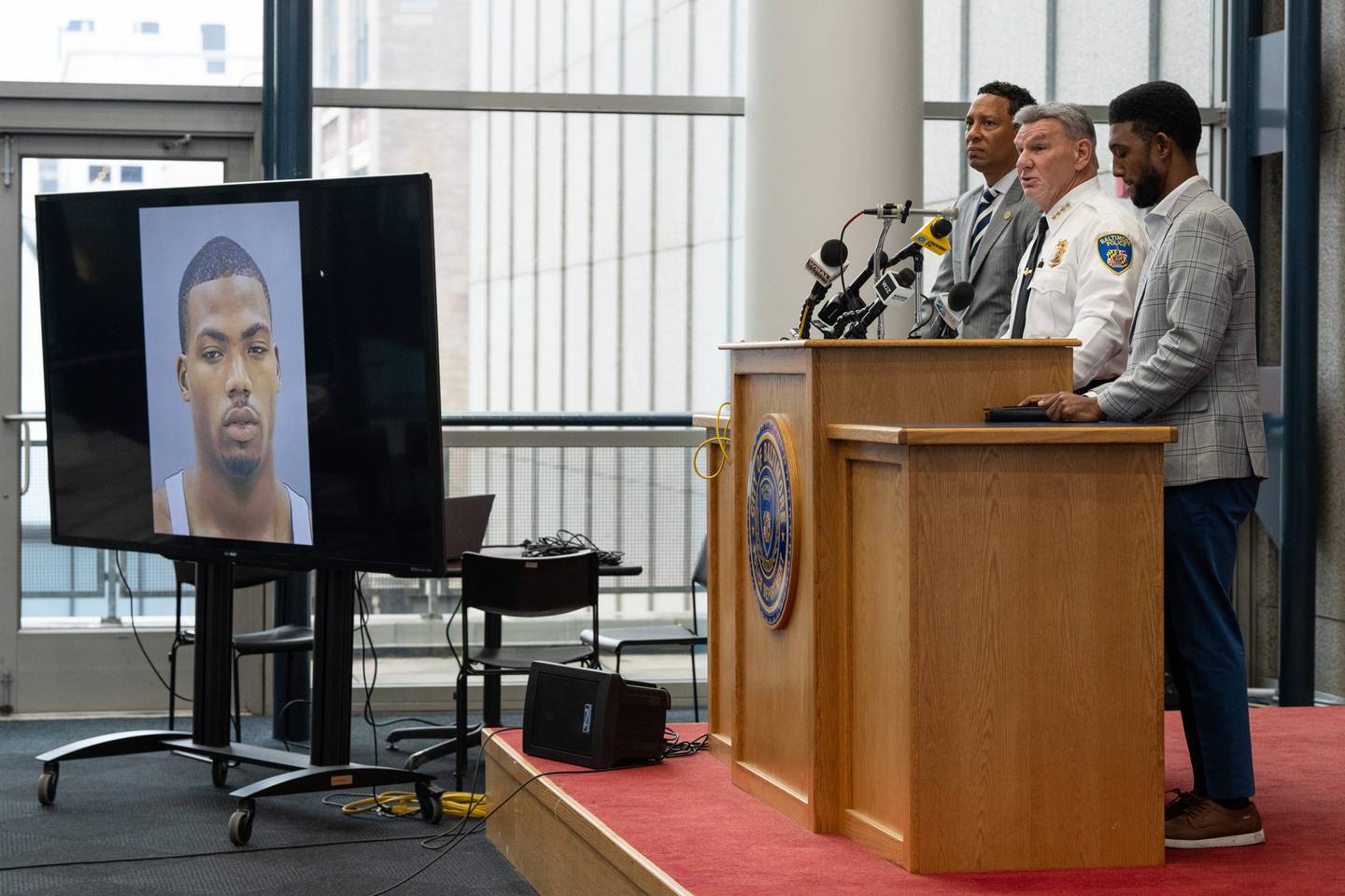 State's Attorney for Baltimore City Ivan J. Bates, Baltimore Police Commissioner Rich Worley and Baltimore Mayor Brandon Scott hold a press conference about the killing of Pava LaPere at BPD headquarters on Tuesday, Sept. 26, 2023. A photo of the suspect, Jason Billingsley, is displayed on the TV.