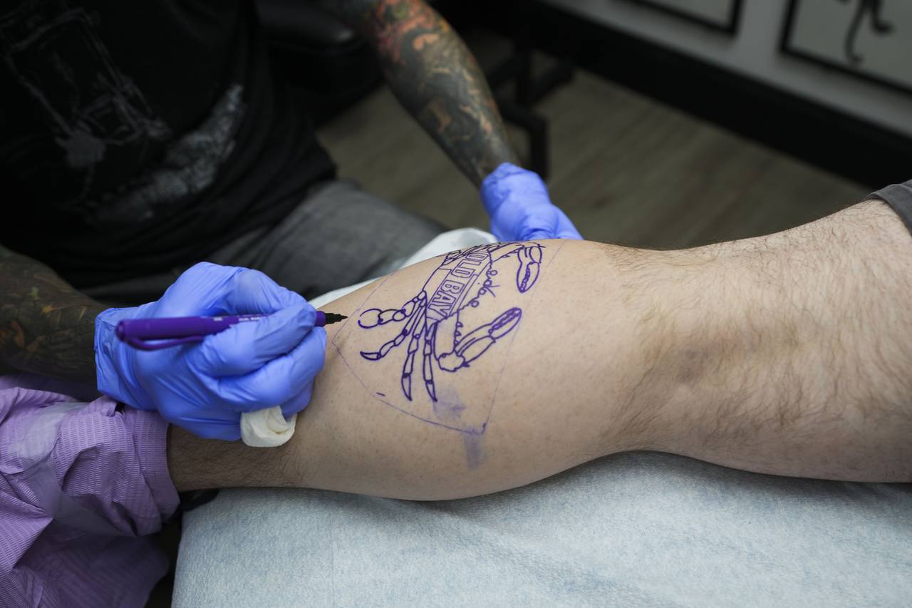 Tory Destromp tattoos a crab on Michael Augliaro.
