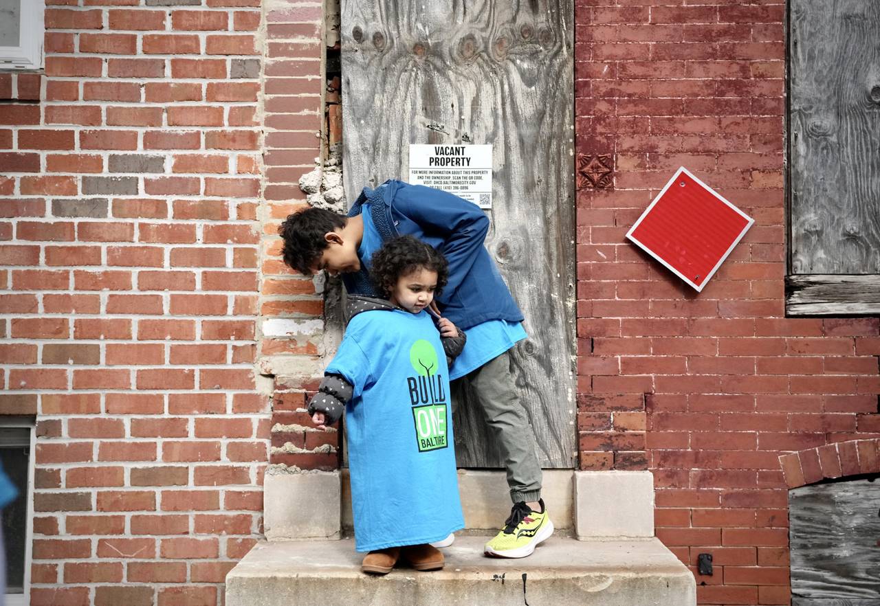 Eliana Wharton and brother Christopher Wharton play outside of a vacant home on West Saratoga street during a press conference hosted by Build One Baltimore on February 16, 2023.