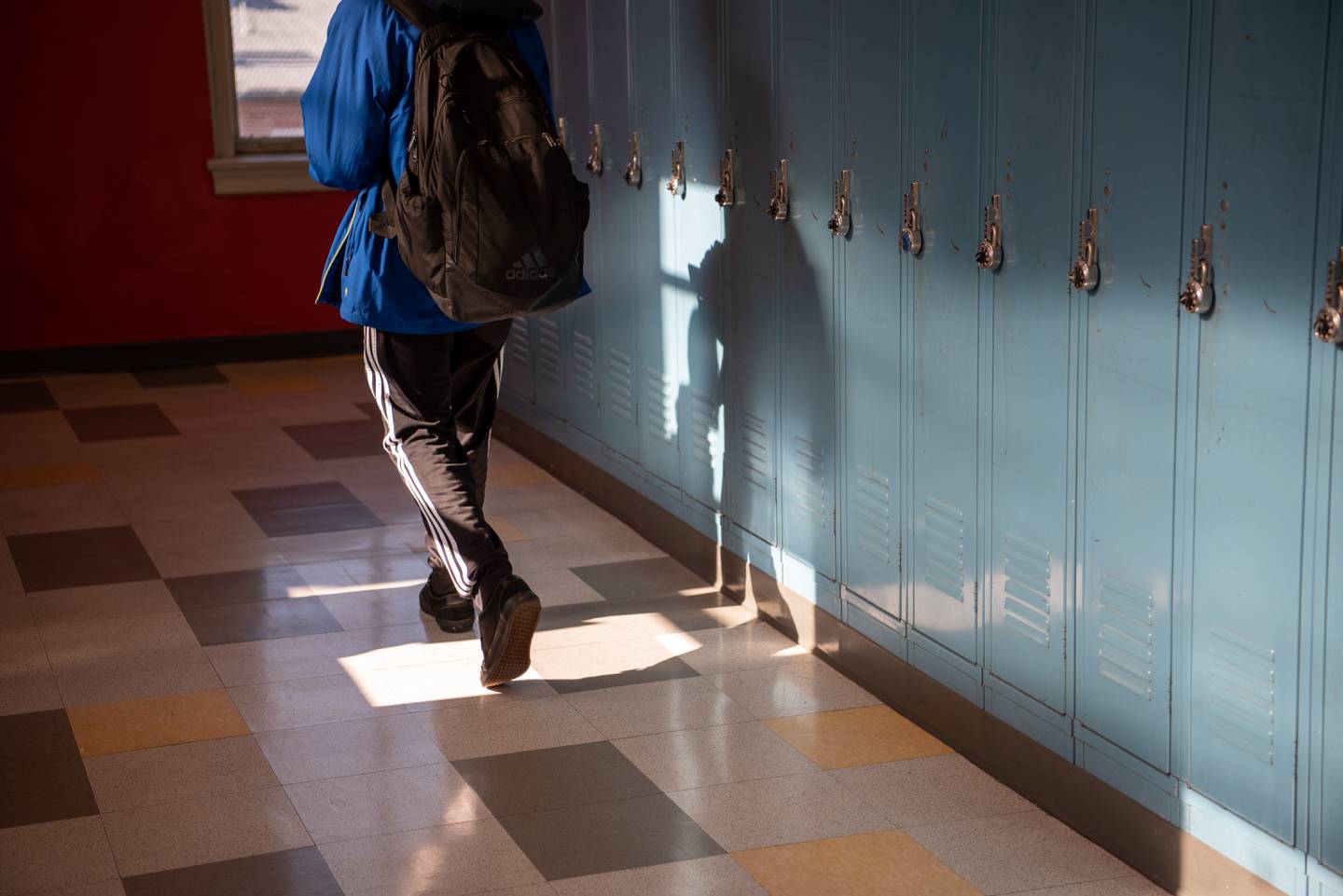 A student walks past lockers in the hallway outside Damien Ford’s Baltimore School for The Arts classroom on Dec. 21, 2022. Ford teaches an African American Literature class where shows his students comparisons between Lauryn Hill lyrics and the work of Zora Neal Hurston.