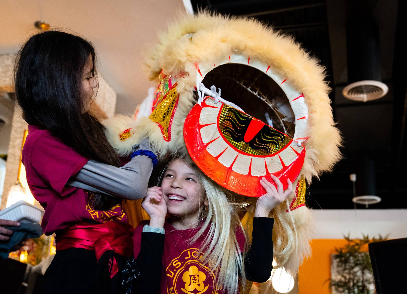 Jaina, right, smiles up at Chloe as she switches in to become the head of the kid lion during a performance at Asian Court in Ellicott City, Md. on Sunday, Feb. 18, 2024.
