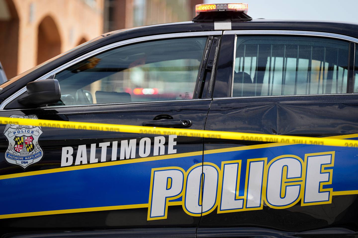 A Baltimore Police car and crime scene tape remains on the scene after a vehicle exploded inside a five-story parking garage in Baltimore’s Fells Point neighborhood on 7/27/22.  Two people are being treated for injuries, fire officials said Wednesday afternoon.