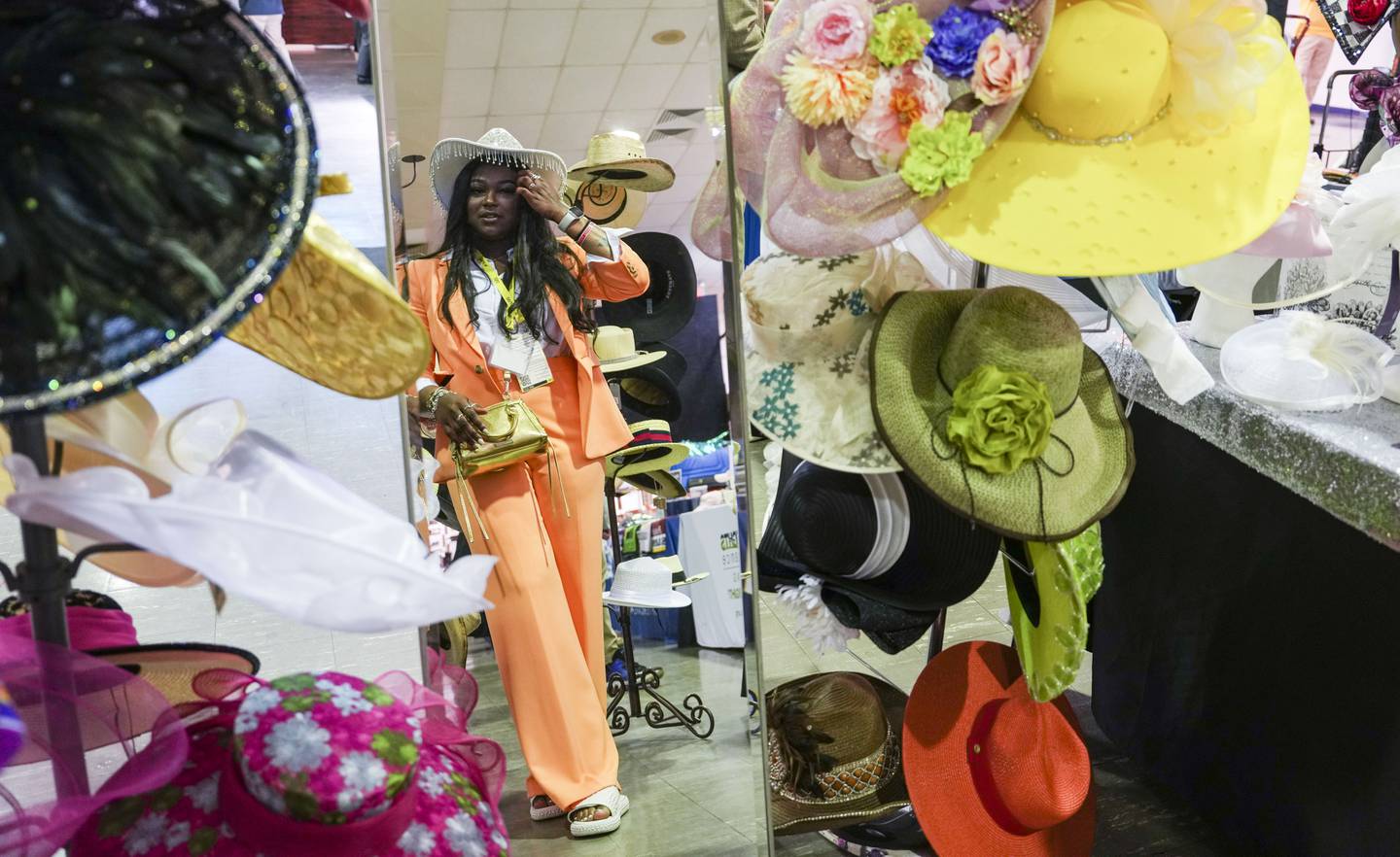 Shaska Davis from Houston, TX tries on a hat at Hats by Marjae at Pimlico during Preakness on May 20, 2023. (Kaitlin Newman/The Baltimore Banner)