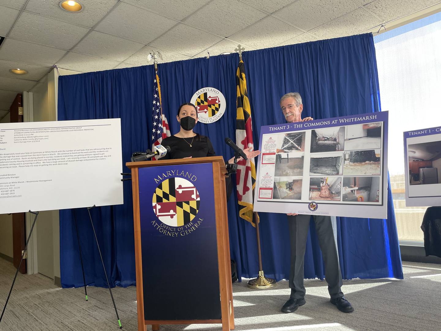 A masked woman speaking at a lectern next to Maryland Attorney General Brian Frosh holding a poster with photos of Westminster Management property.