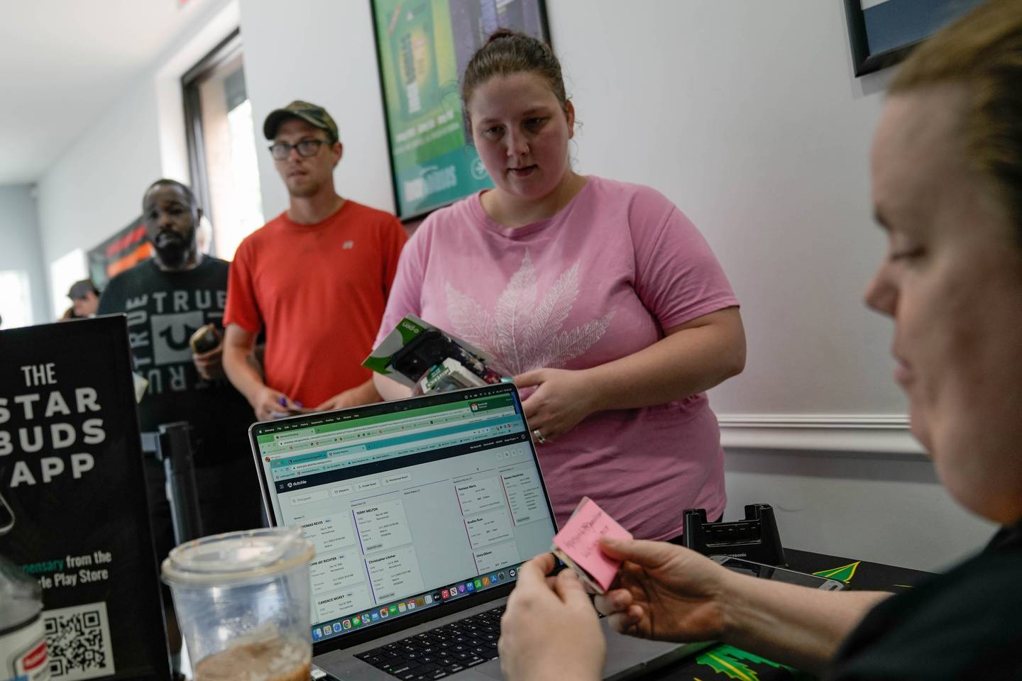 Before she goes into the dispensary, Heather Pielert's ID is checked by a Star Buds employee, while Joshua Revis waits behind her on July 1, 2023, Maryland's first day of recreational cannabis legalization.