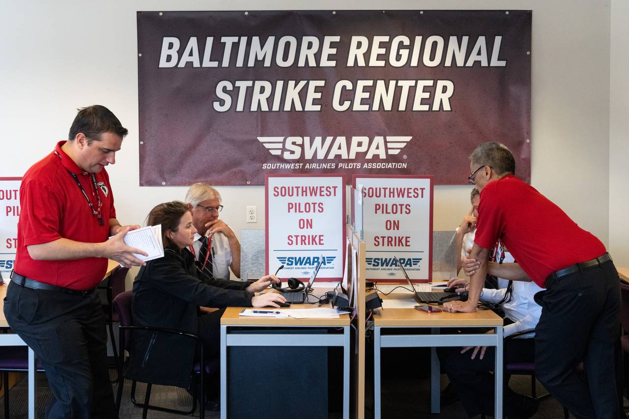 Southwest Airlines pilots learn how to do pilot tracking, with a large banner reading "Baltimore Regional Strike Center" hanging on the wall behind them.