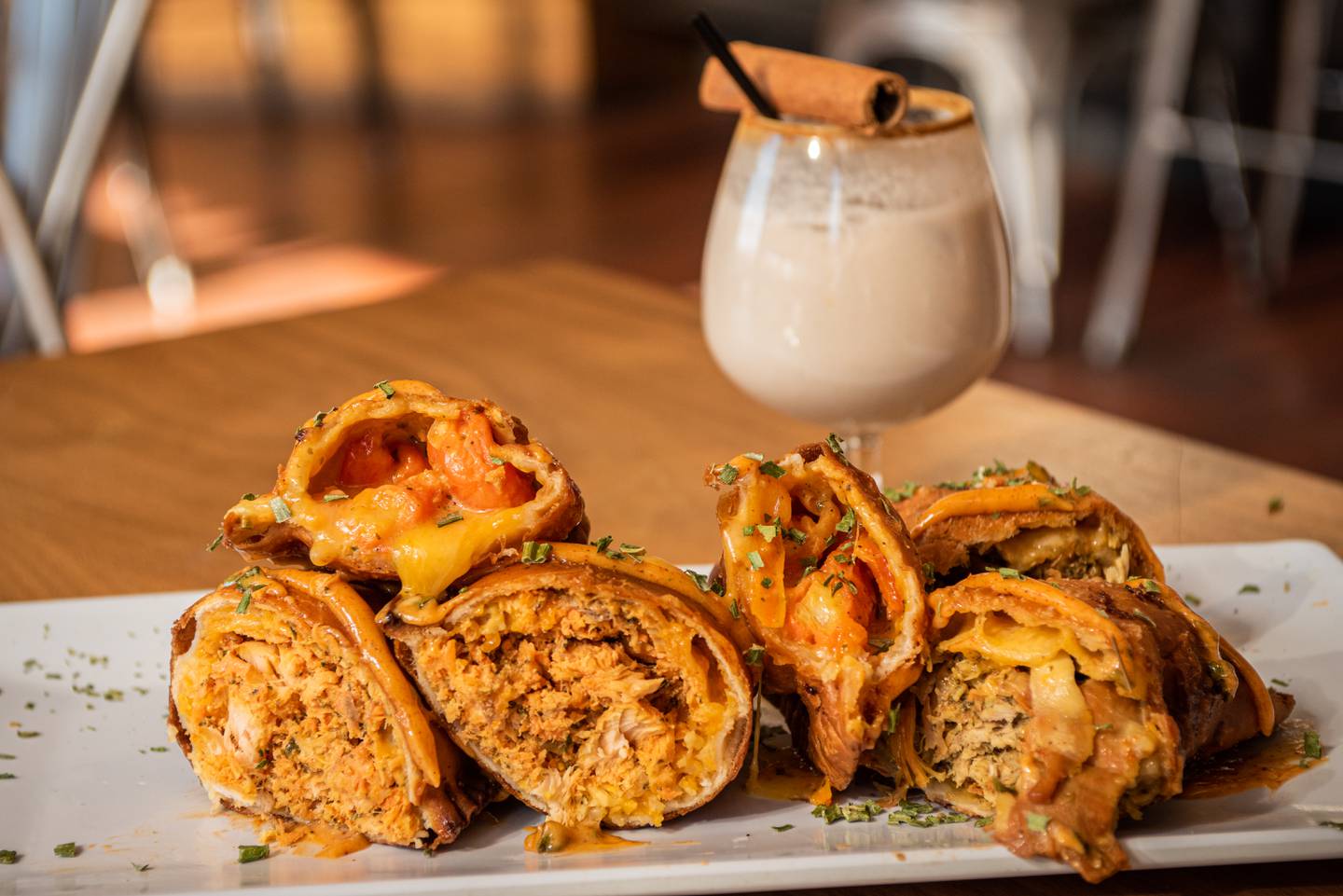 A plate of empanadas accompanied by a glass of coquito sits on the counter inside Elisa Milan's restaurant: the Empanada Lady.
