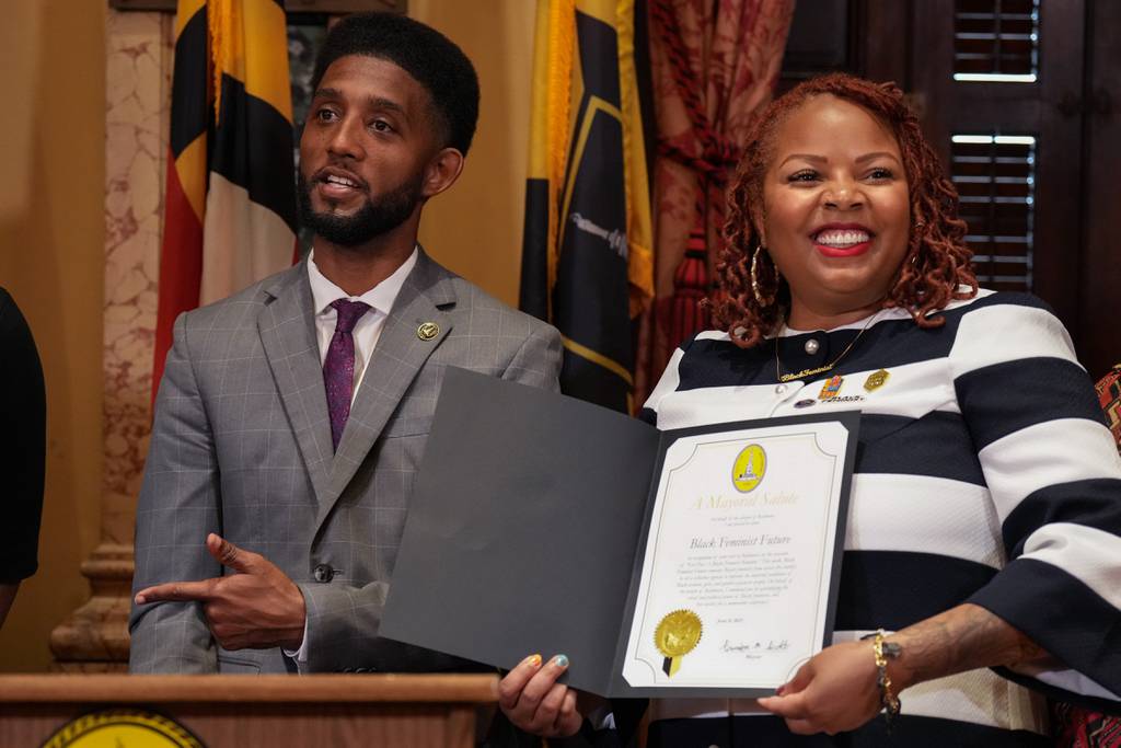 Mayor Brandon Scott, left,  presents a Mayoral Salute to Paris Hatcher, executive director and founder of the Black Feminist Future organization, at a ceremony inside Baltimore City Hall on Thursday, June 8, 2023.