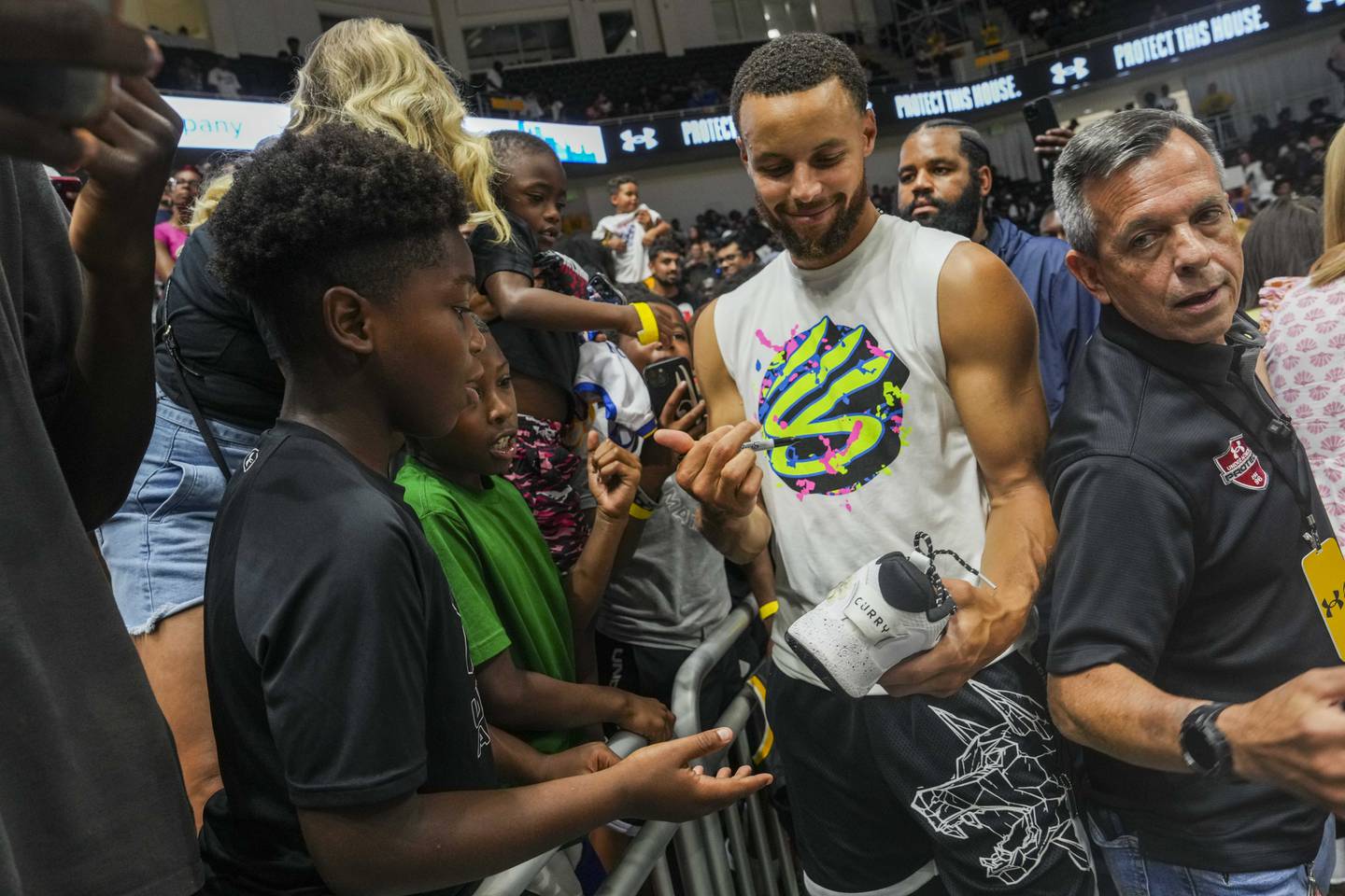 Warriors basketball player Stephen Curry signs items for fans at the Stephen Curry Baltimore Showcase Live at UMBC on August 17, 2023.
