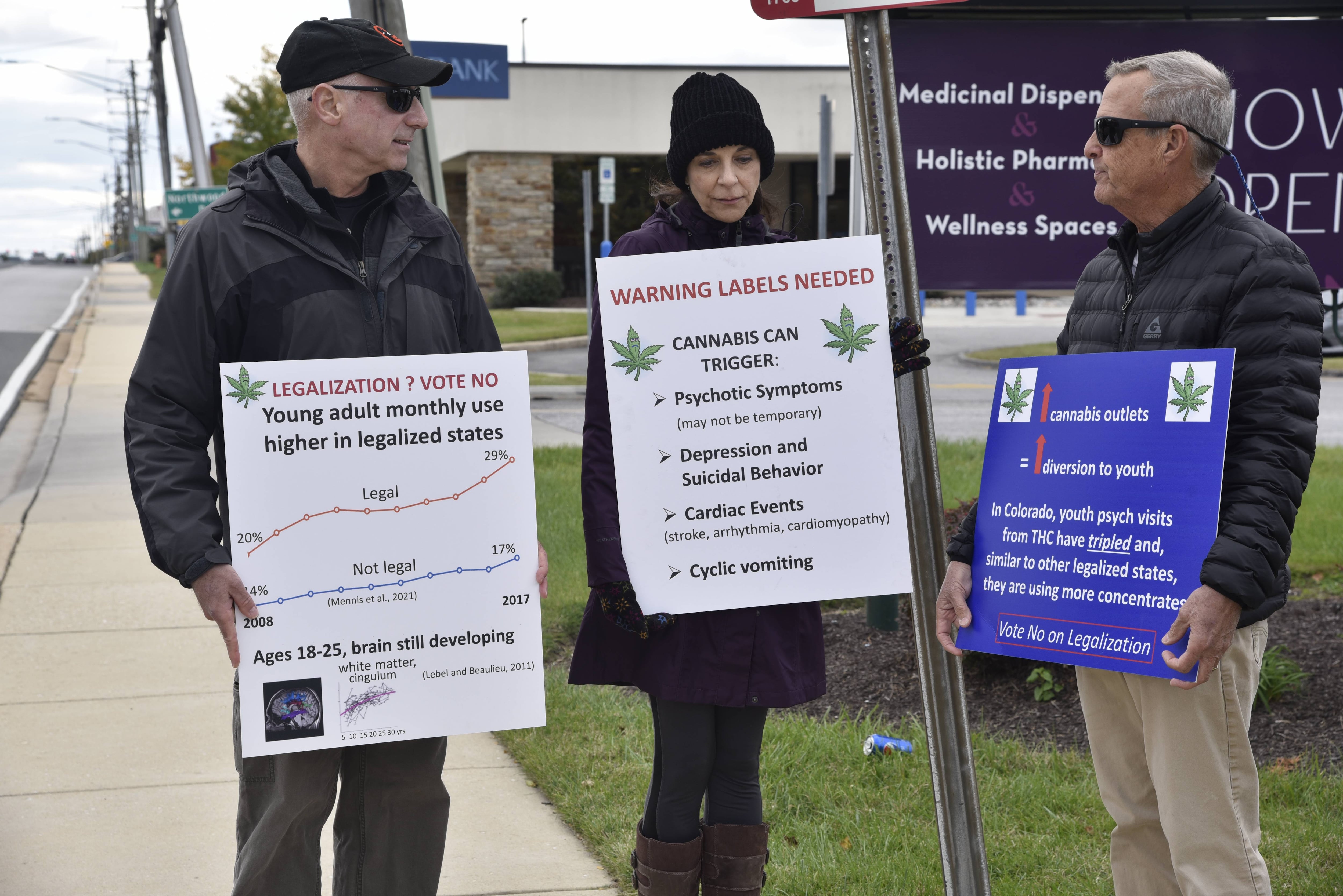 Mark Marchione (left), his wife Deborah, of northern Baltimore County, and Kevin Becker, a Sparks Glencoe geneticist retired from the National Institutes of Health, display signs opposing the November referendum to approve adult-use cannabis in Maryland.
