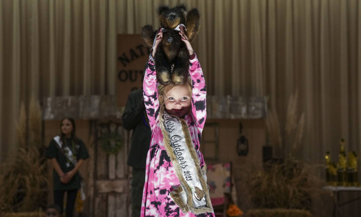 Little Miss Outdoors 2023 holds up a teddy bear made of muskrats during the live auction. The bear fetched $2,000.