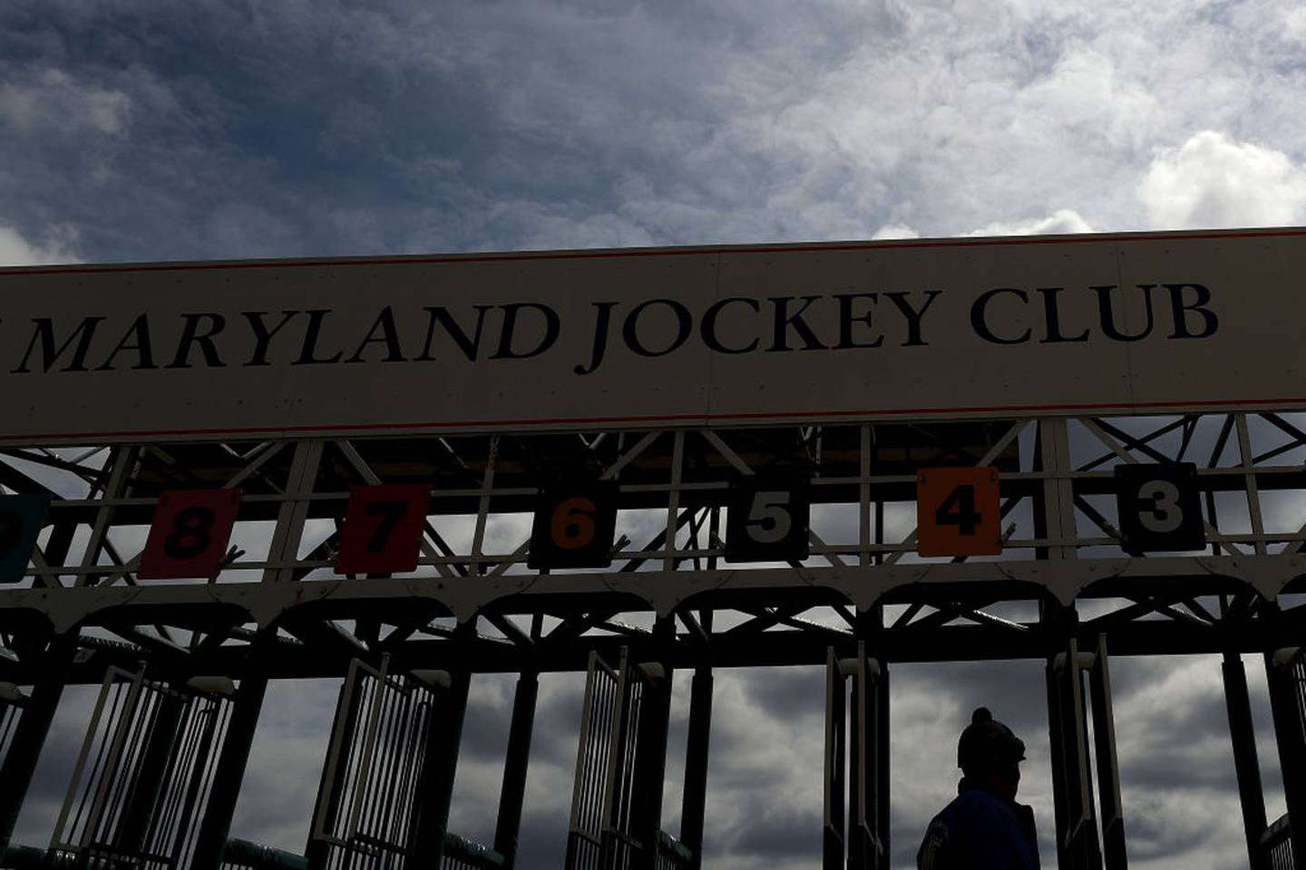 LAUREL, MARYLAND - MARCH 15: A man walks in front of a starting gate as horses and jockeys prepare to race without spectators at Laurel Park on March 15, 2020 in Laurel, Maryland. Nearly all of professional sports have been canceled or postposed because of the Coronavirus pandemic, except for horse racing. However, today Maryland Gov. Larry Hogan issued an emergency order to close all Maryland casinos, racetracks, and simulcast betting facilities to the general public due to COVID-19.