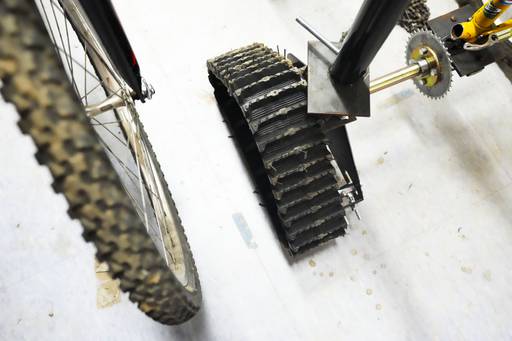 An ATV wheel is attached to the back of a bike to help it get through the mud part of the obstacle course.