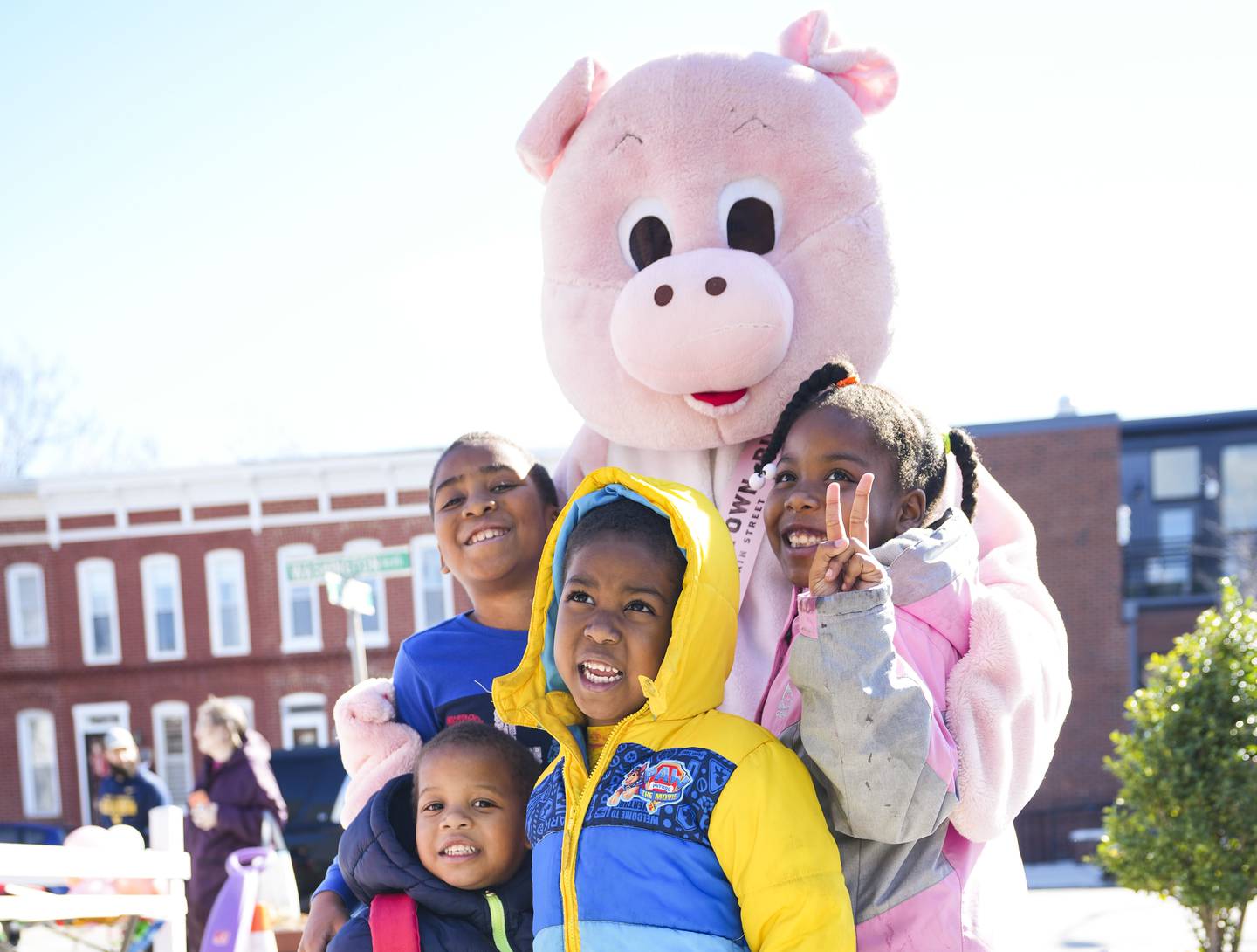 Pigtown mascot, Piggleton, takes a picture with (right to left) Amani Thompson (7), Judah Thompson (4), Titus Thompson (8), Simeon Thompson (2) during the 3rd annual Pigtown neighborhood celebration of National Pig Day, in Washington Village, March 4, 2023.