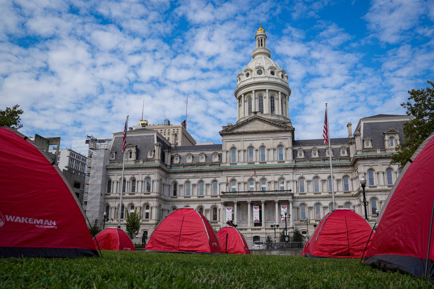 Red tents occupy the lawn at the homeless encampment outside City Hall on August 17, 2022. The Black Community Development Coalition and homeless advocates set up an encampment Wednesday at the War Memorial Plaza to encourage Baltimore leaders to make the encampments around the city more of a priority.